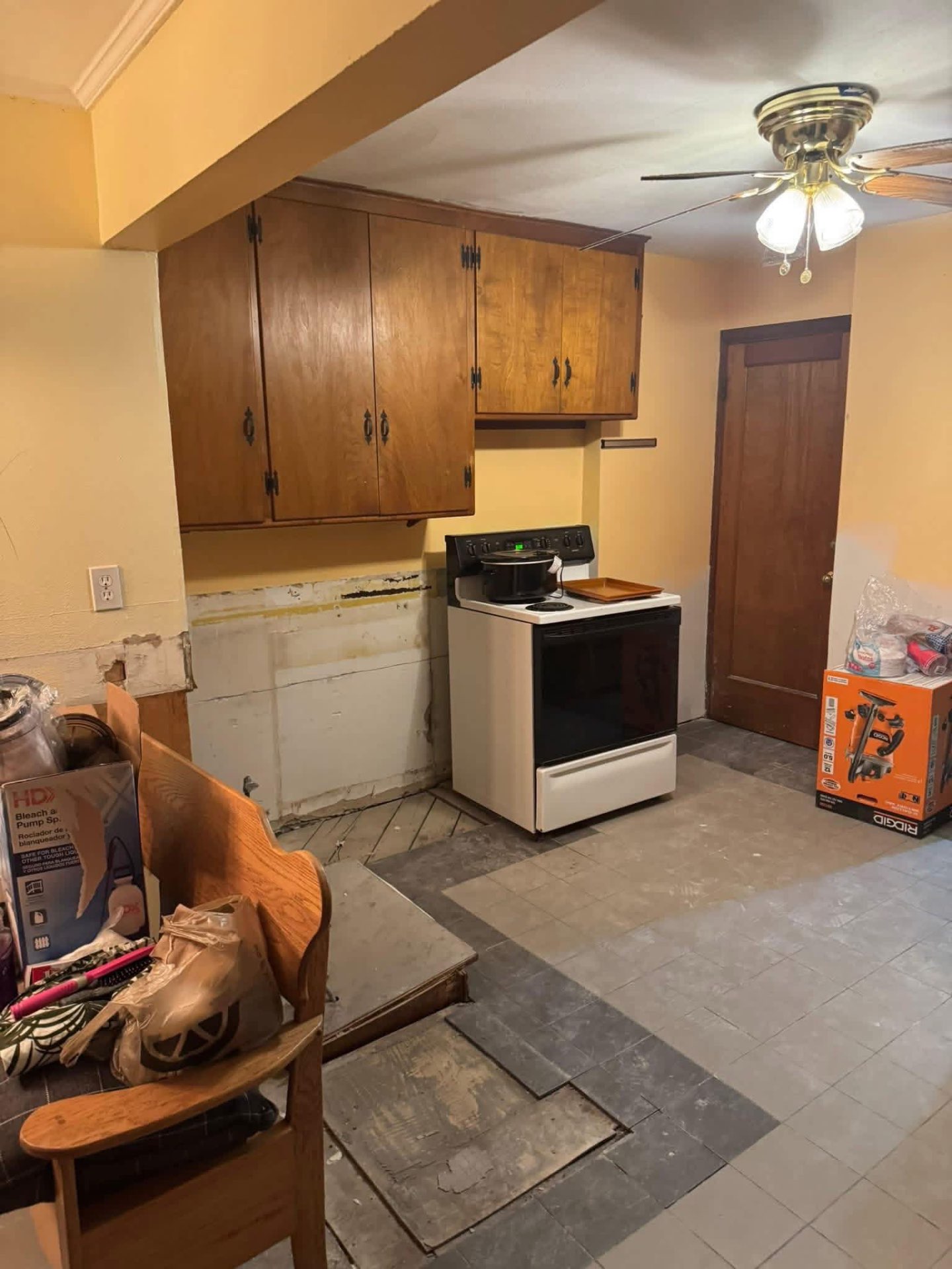 Dated kitchen with wooden cabinets, stove, and worn flooring before renovation